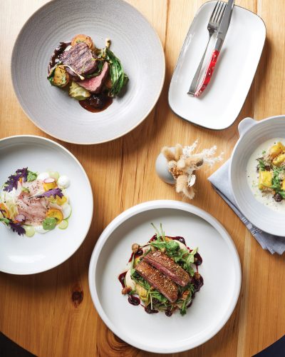 Clockwise from top: Brunson Meat Co. dry-aged N.Y. strip, agnolotti, pan-roasted duck breast, and hamachi crudo