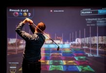 Man swinging infront of golf simulator screen