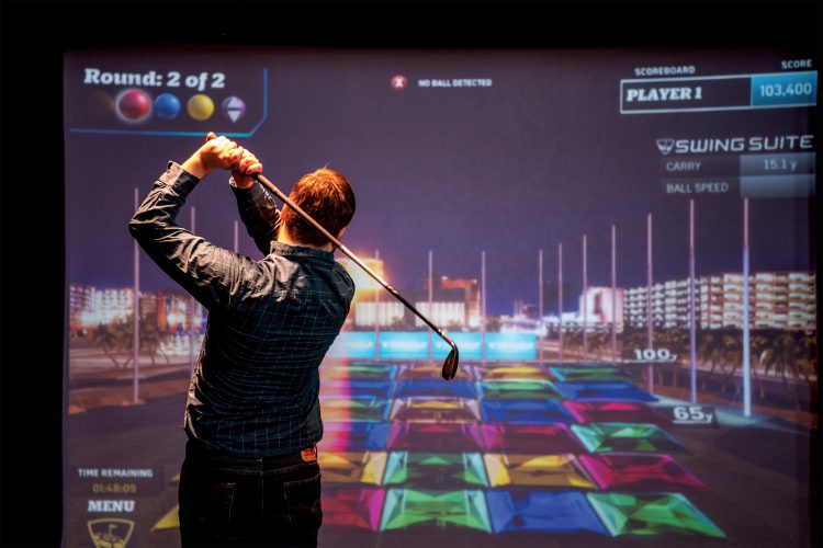 Man swinging infront of golf simulator screen