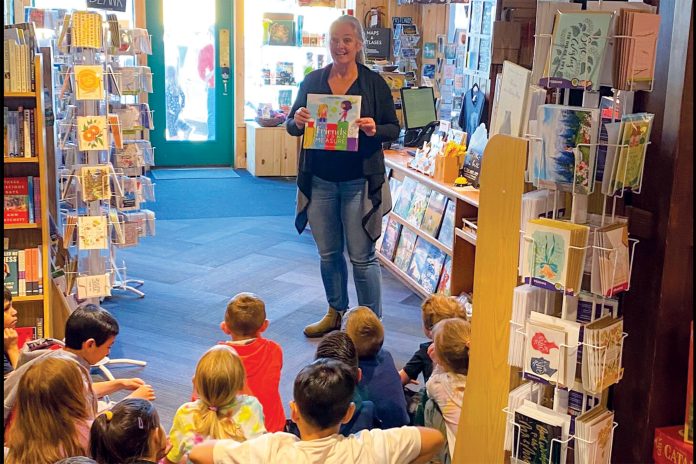 Woman shows book to group of children inside Off the Beaten Path Bookstore and Café