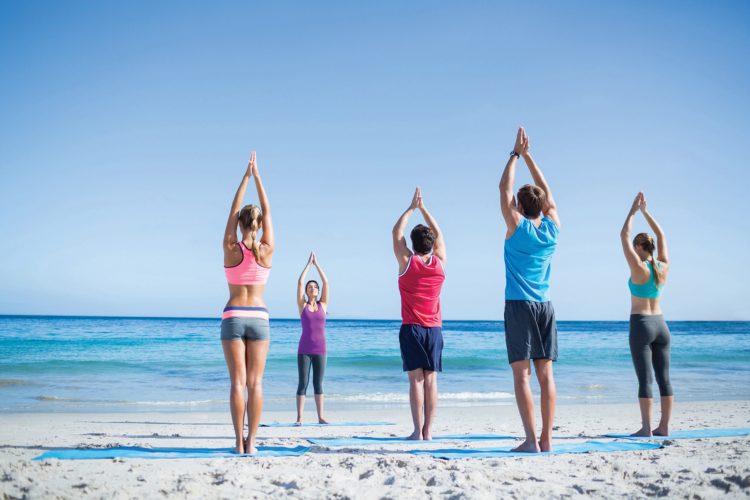 People doing yoga on the beach.