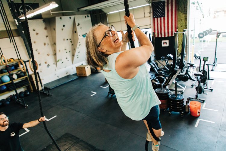 A woman climbs a rope at Axistence Athletics.