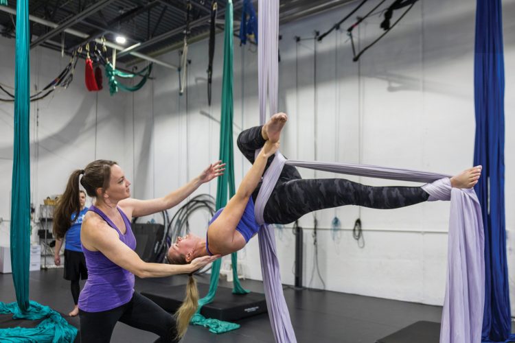 A woman participating in an aerial dance fitness class at Aerial Cirque Over Denver.