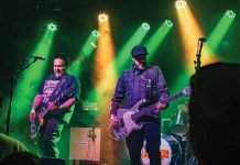 Two men play guitars on stage at Globe Hall.