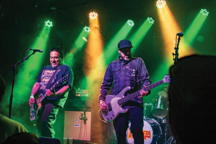 Two men play guitars on stage at Globe Hall.
