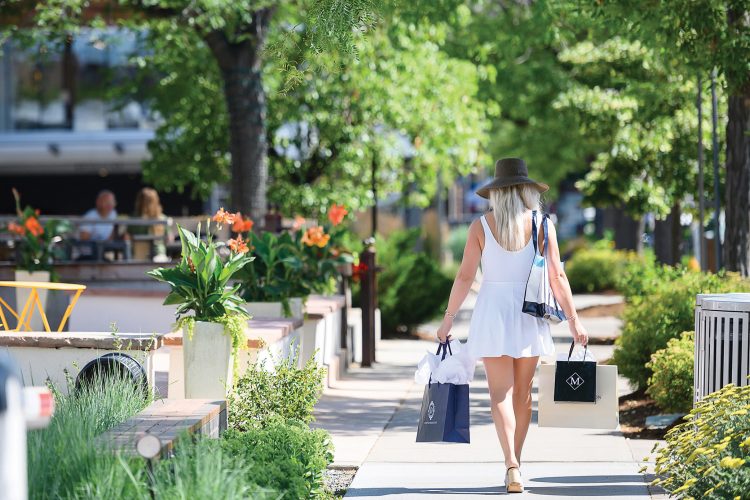 A woman walks with shopping bags at Cherry Creek North.