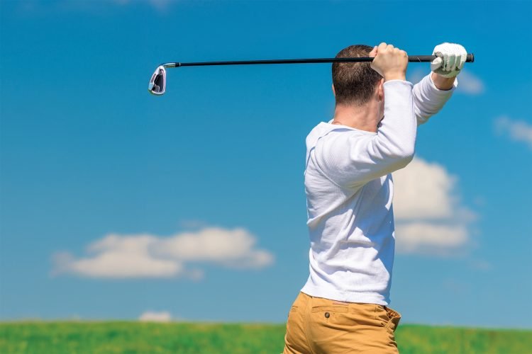 A golfer swings his golf club.