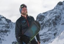 Conor Hall stands with his snowboard.