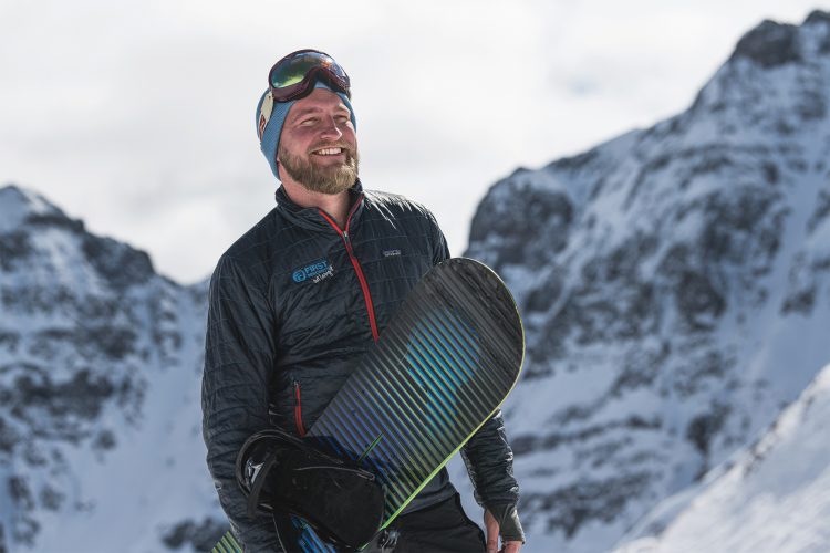 Conor Hall stands with his snowboard.