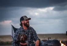 Anthony Ferro relaxes by a fire with a hunting dog