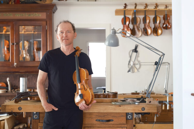 Will Scherer posing with a violin at Scherer Violin Shop.