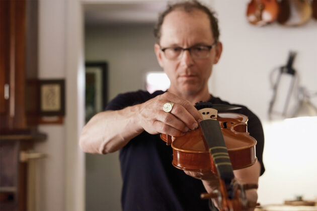 Will Scherer examining a violin at Scherer Violin Shop.