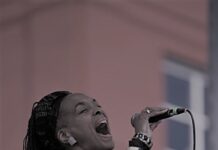 Black-and-white photo of singer Linda Theus-Lee performing onstage, holding a microphone mid-song.