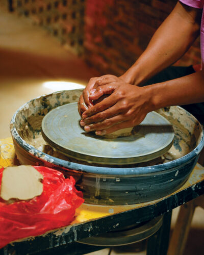 Person works on pottery wheel.