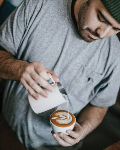 Person makes latte at coffee workshop.