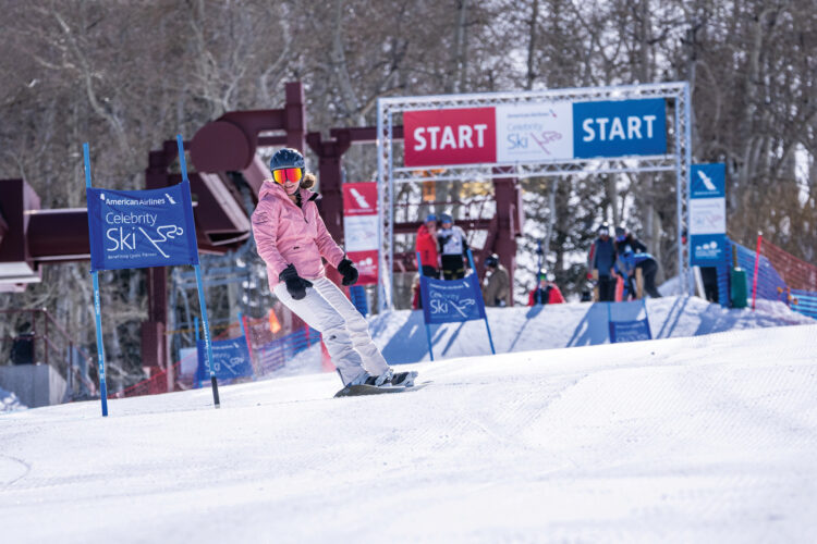 Girl snowboards in a race at American Airlines Celebrity Ski weekend.