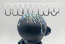 Promotional image of a customized KidRobot MUNNY figure standing against a light gray background. The black vinyl character is covered in small, colorful bead-like embellishments across its head and body, creating a textured, sculptural surface. The word “MUNNY” appears above the figure in bold lettering, emphasizing the designer toy theme.