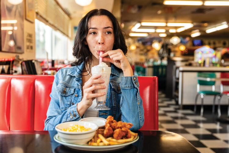 Woman sips milk shake at Guther Toody's Diner.