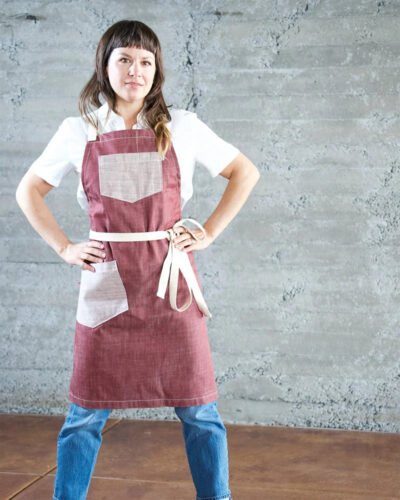 Woman poses in an apron from Valentich Goods.