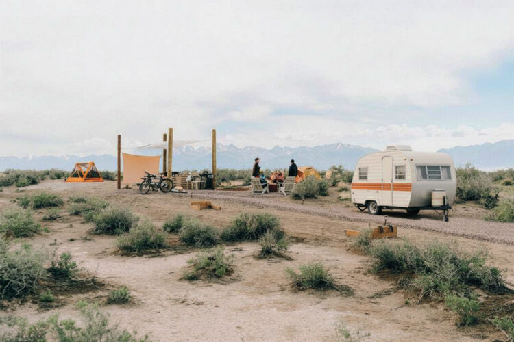 People relax around a campfire with an RV  at Ramble Camp.