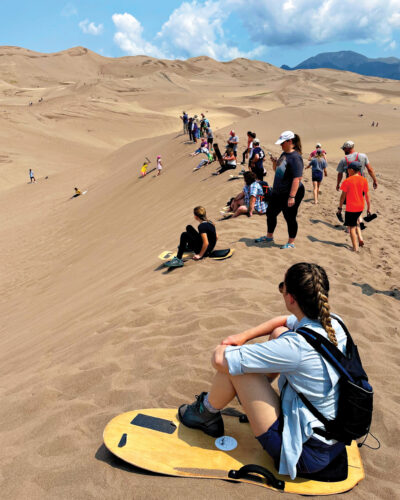 People walk and sit on the Great Sand Dunes.