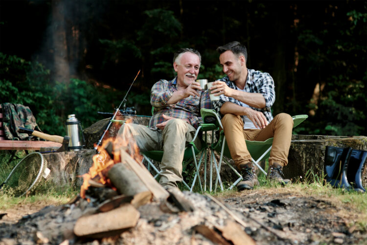 People drink coffee by a campfire.