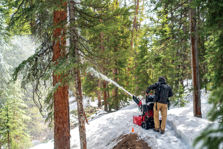 Person clears snow off of trail at Keystone Resort.
