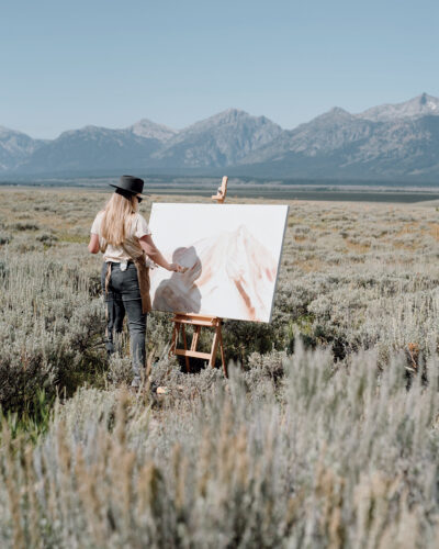 Kelly Peters paints in a field facing the Front Range mountains.