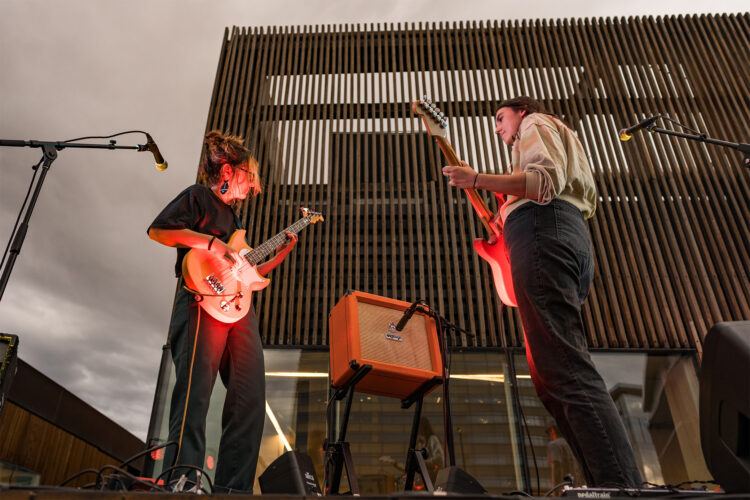 Two people play guitars on stage.