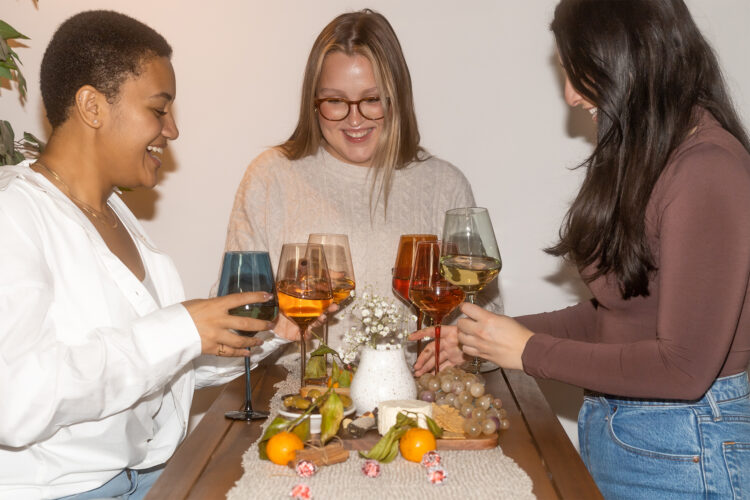 Women cheers wine glasses from Saludi Glassware.
