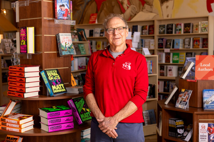 Man poses with books at Denver Book Society.