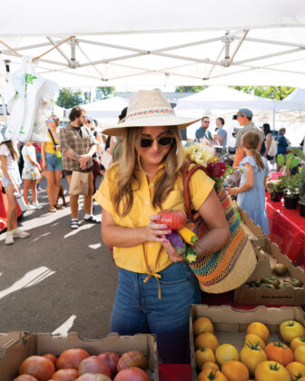 Person shops for veggies at a Denver farmers market.