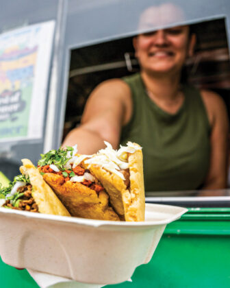 Person hands food out of food truck window.