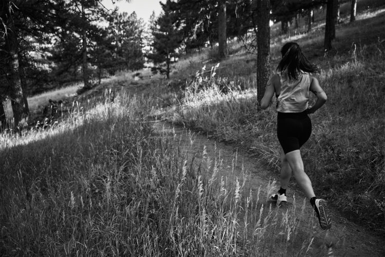 Woman runs on trail wearing Notace shoes.