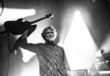 Keith Moseley, from The String Cheese Incident, lifts his guitar into the air on stage.