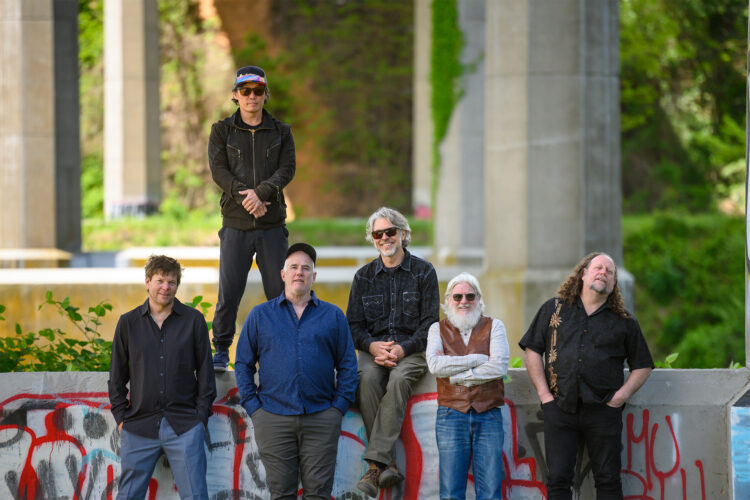 Band members of The String Cheese Incident pose together in front of a venue.