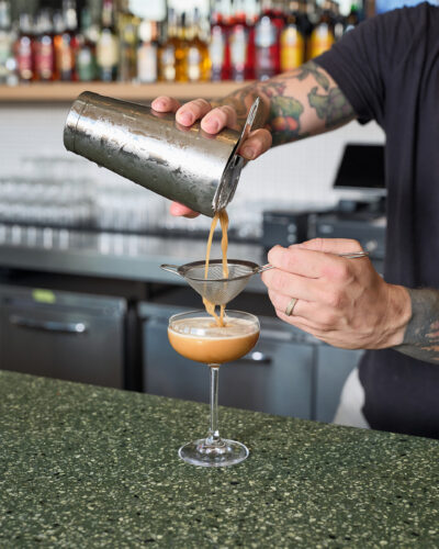Bartender pours a cocktail at Paperboy Denver.