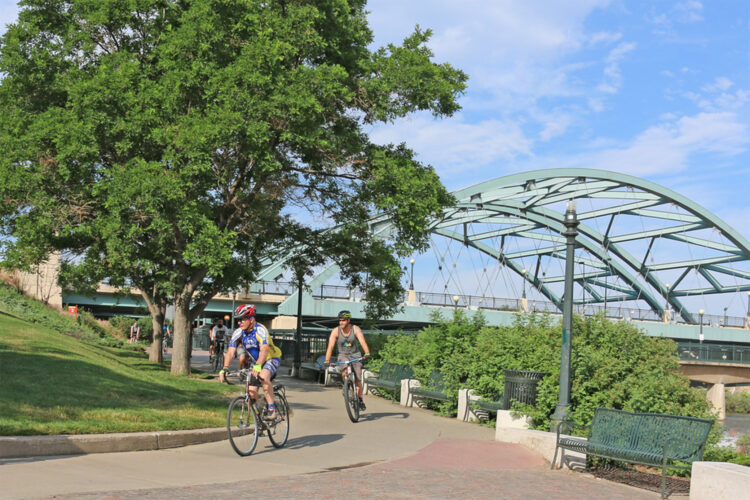 People bike under a bridge in Denver.