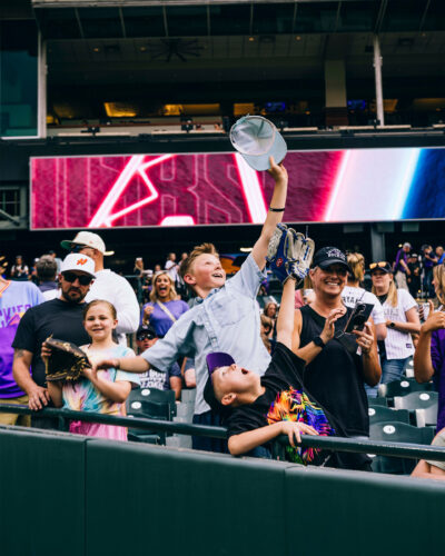 Children try to catch a ball in the stands of Coors Field.