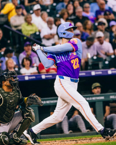 Rockies player hits baseball at Coors Field.