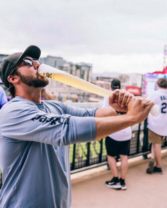 Man drinks "beer bat" drink at Coors Field.