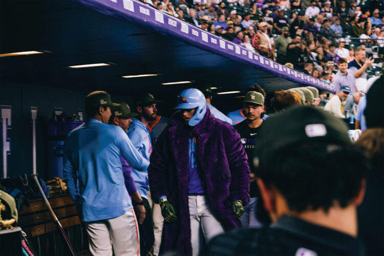Player wears the Rockies purple faux-fur home run celebration coat in the dugout at Coors Field.