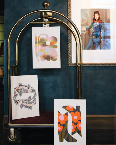 Prints from Parrott Paints hang on a hotel bell cart.