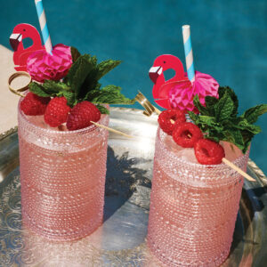 Two pink Amber Eyes cocktails with flamingo straws.
