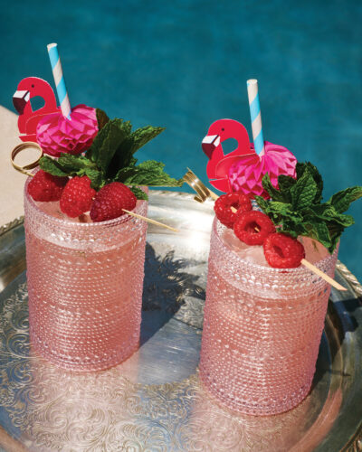 Two pink Amber Eyes cocktails with flamingo straws.