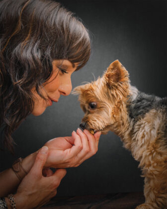 Woman feeds dog a treat in a photo by Fetch Photo Truck.