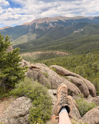 Person sits on the edge of a mountain while on a hike in Manitou Springs.