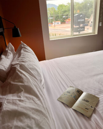 Bed with Manitou Springs guide at The Outrider Hotel.