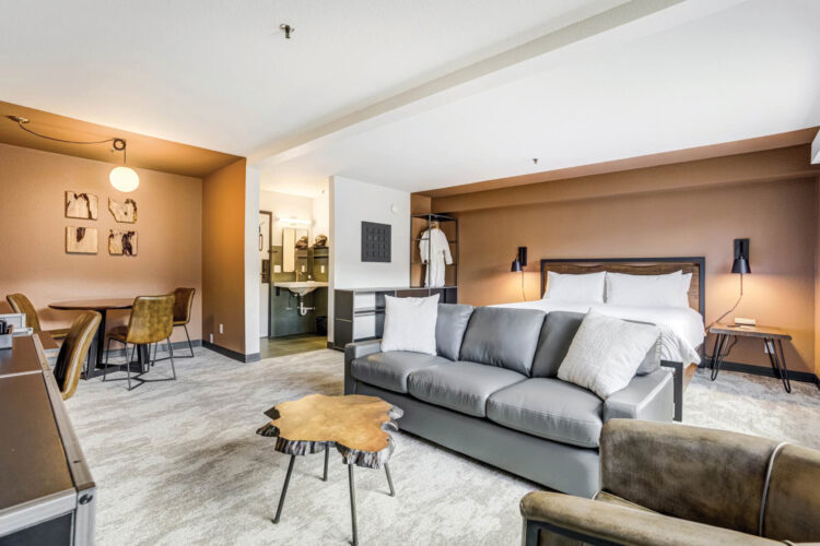 Interior suite with king bed, 4 seat dining area, and sitting area at The Outrider Hotel.