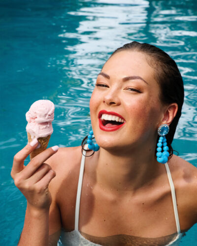 Woman eats ice cream in pool.